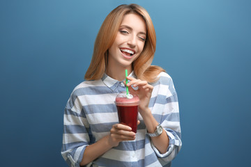 Beautiful young woman with fresh smoothie on color background