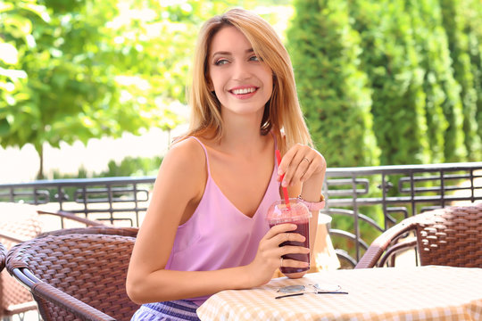 Beautiful young woman with fresh smoothie in cafe