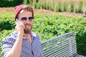 Fototapeta premium Young hipster man talking on phone in park