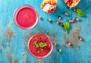 Glasses with delicious pomegranate smoothies on wooden background