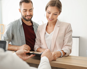 Female receptionist and young couple in hotel