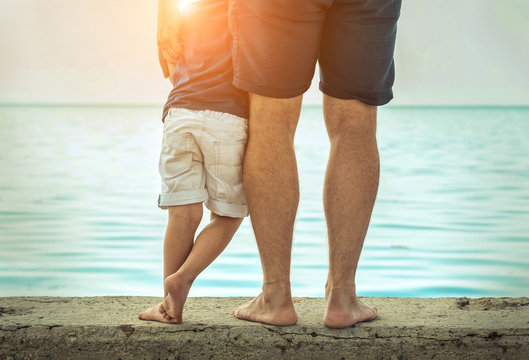 Father and son stay on the sea beach under sunlight at summer ti