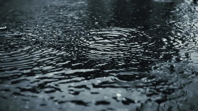 Raindrops and rain circles in puddle, super slow motion
