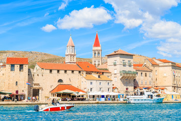 Motorboat sailing on sea along Trogir old town with historic buildings, Dalmatia, Croatia