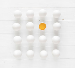 White raw eggs n rows with one yolk on a white wooden table