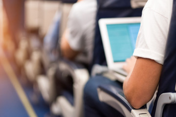 Naklejka premium Man typing on a laptop aboard the plane