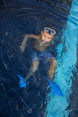 Fototapeta na wymiar Little child with goggles swimming in the water