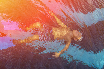 Little child with goggles swimming in the water. Toned