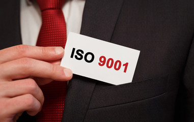 Businessman putting a card with text ISO 9001 in the pocket