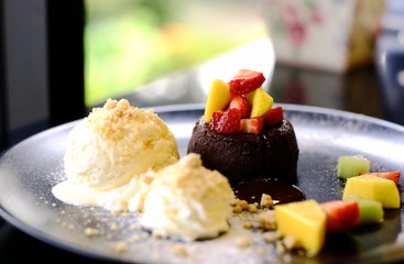 chocolate lava cake , ice cream and various small fruit in a white dish are great dessert in a restaurant.