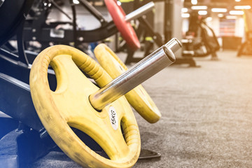 Heavy yellow weights sitting on the floor of modern gym place, other equipment on background