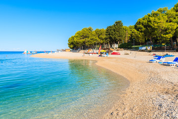 Pebble stone beach with crystal clear azure sea water in Primosten town, Dalmatia, Croatia
