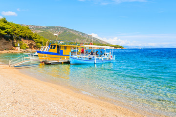 Tourist and fishing boats on beautiful Zlatni Rat beach in Bol town, Brac island, Croatia