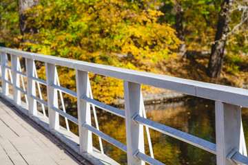 Fototapeta premium Wooden footbridge over the river a bright autumn day