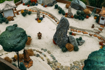 Miniature houses, toy landscape objects on the sand. Anti-stress and soothing sand therapy