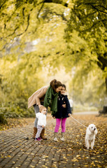 Fototapeta premium Mother and two girls walking with a dog in the autumn park