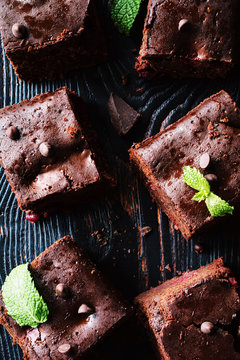 Dark chocolate brownies decorated with mint leaf on dark background. Top view, vertical composition