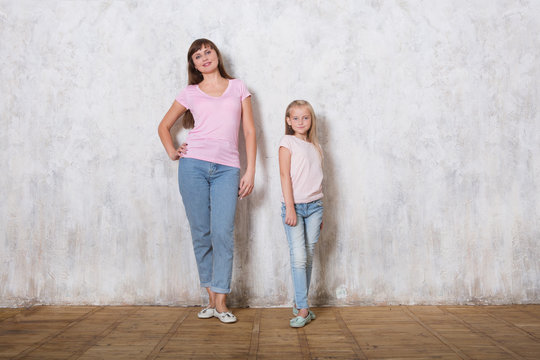 Beautiful Mom With Her Daughter Posing Against Gray Wall, Minimalist Street Fashion Style, Family Same Look.