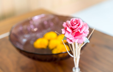 Obraz na płótnie Canvas Artificial pink rose on wooden table