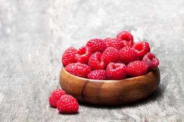 Fresh  selected raspberries on wooden bowl on rustic table