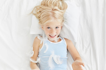 Childhood, bedtime and happiness concept. Freckled appealing girl wears night clothes, plays with...
