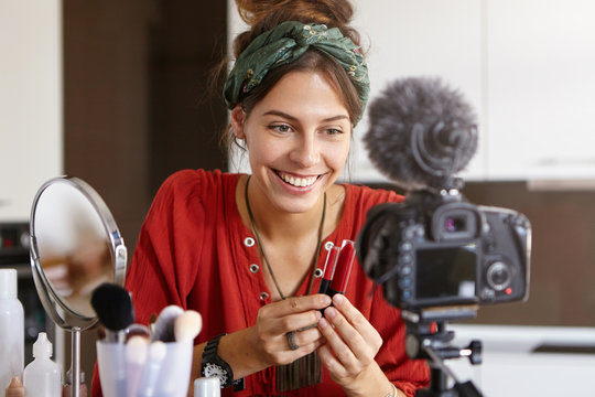 Talented well known cosmetologist, has own blog, explains difference between two lip glosses, gives recommendations and advice. Cheerful woman presents cosmetics for website. Beauty, techology concept