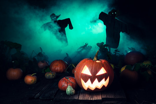 Scary pumpkin with green mist and scarecrows for Halloween