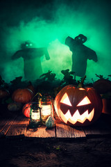Orange Halloween pumpkin on dark field with scarecrows