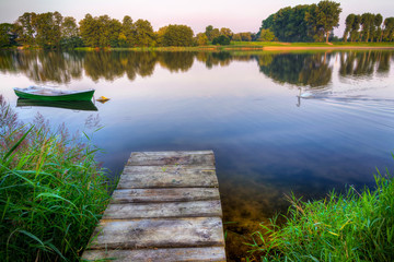 Rowing boat floating over calm waters. Early morning. HDR. Masuria, Poland.
