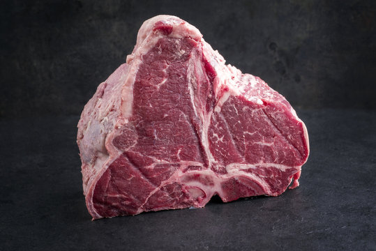 Raw dry aged wagyu porterhouse steak as close-up on a black slate