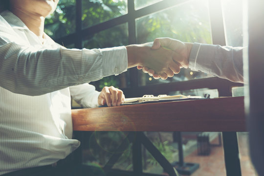 Businessmen shake hands with congratulations on business deal or dealBusiness concept succeeds. (With lens flare)