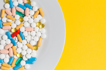 Obraz premium Many pills on a plate isolated on yellow background