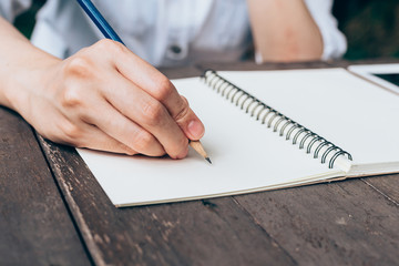 Hipster woman hand writing notebook paper in coffee shop.