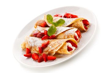 Crepes with strawberries and cream on white background 