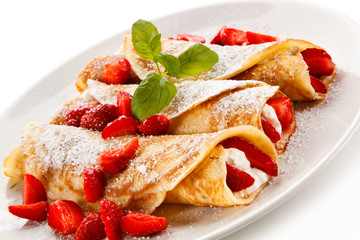 Crepes with strawberries and cream on white background 