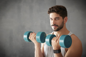 Young man lifting a dumbbell in the gym