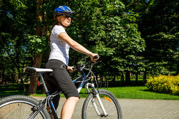 Fototapeta na wymiar Healthy lifestyle - woman riding bicycle in city park 