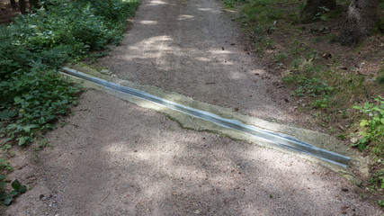 Metal storm rain drainage on a path in the mountains