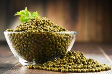 Composition with bowl of vigna mungo bean on wooden table.