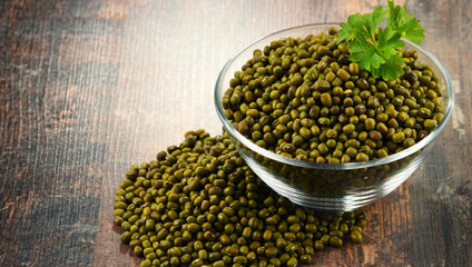 Composition with bowl of vigna mungo bean on wooden table.
