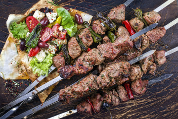 Traditional shashlik with salad and yufka bread as top view on an old burnt cutting board