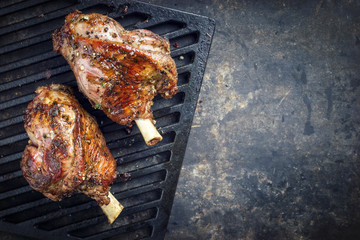 Two barbecue leg of lamb as top view on cast iron grillage