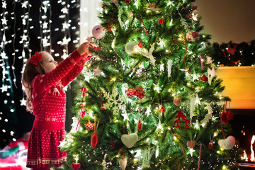 Child decorating Christmas tree. Xmas for kids