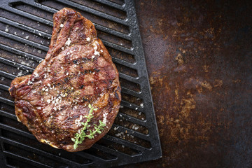 Barbecue dry aged Rib of beef with salt and pepper as top view on a grillage
