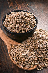 Composition with bowl of shelled sunflower seeds on wooden table