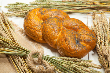 Wicker bread and wheat on a white wooden background
