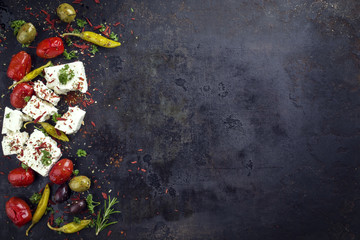 Traditional Greek feta with vegetable and peperoni as top view with copy space right on an old rustic board - obrazy, fototapety, plakaty
