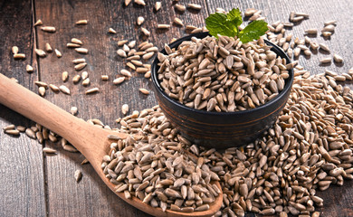 Composition with bowl of shelled sunflower seeds on wooden table