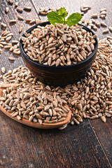 Composition with bowl of shelled sunflower seeds on wooden table