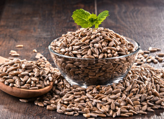 Composition with bowl of shelled sunflower seeds on wooden table
